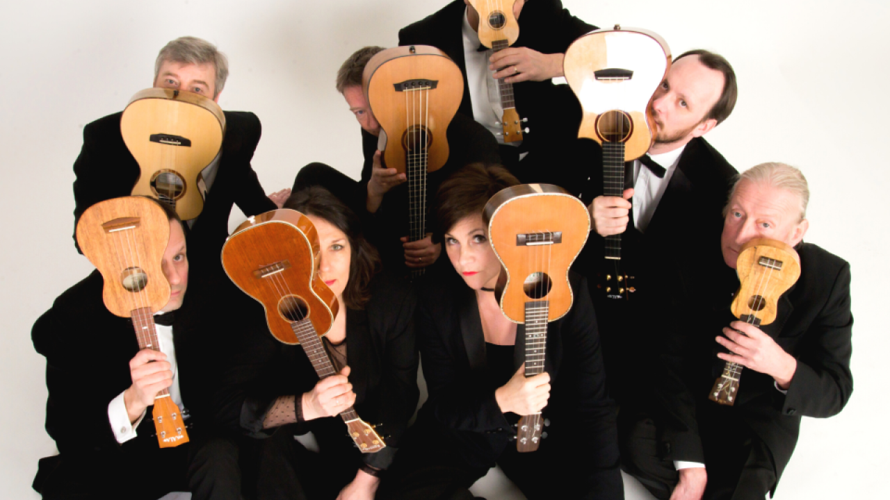 Band of people in black suits holding ukuleles