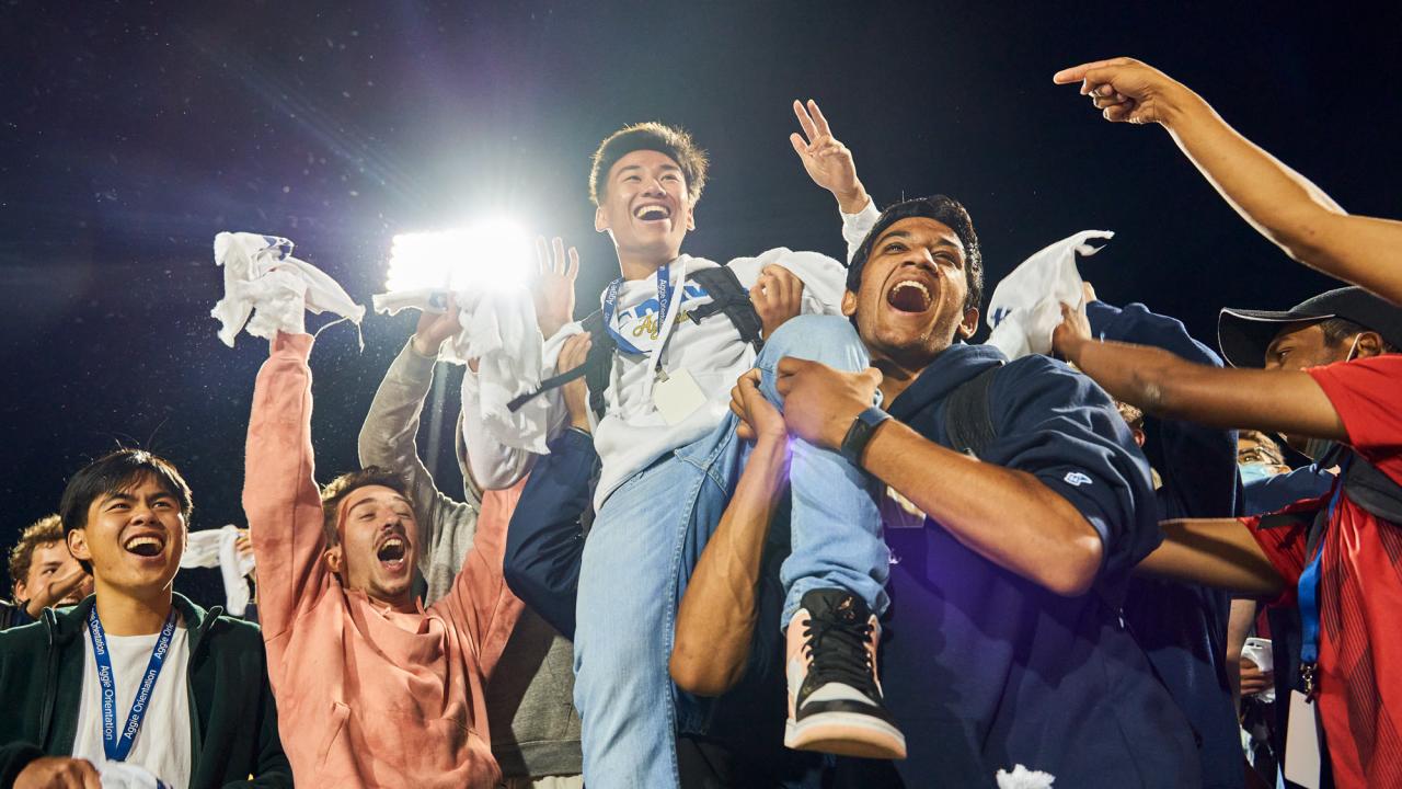 Jubilant Aggie football fans lift one of their own into the air.