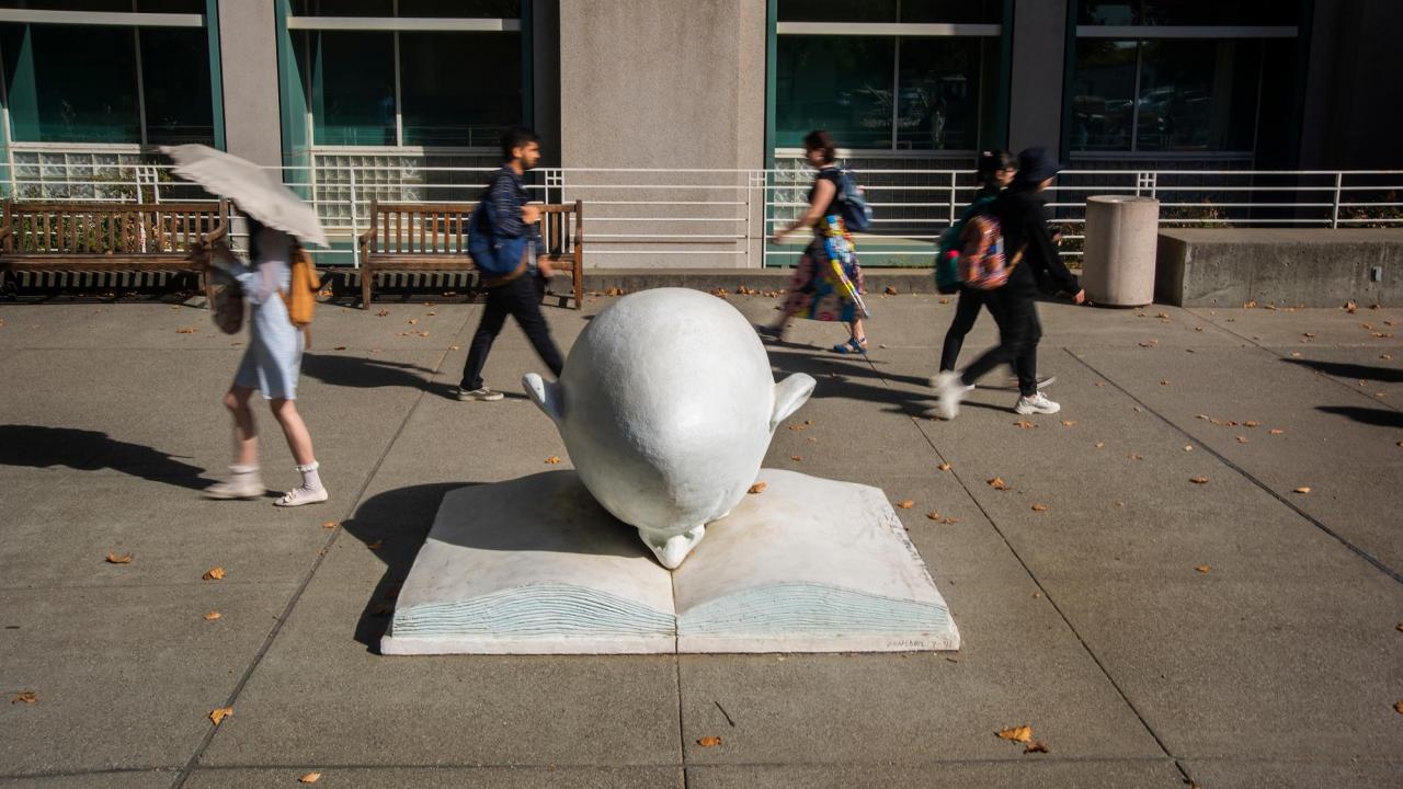 Students walk by the Bookhead sculpture on the UC Davis campus.