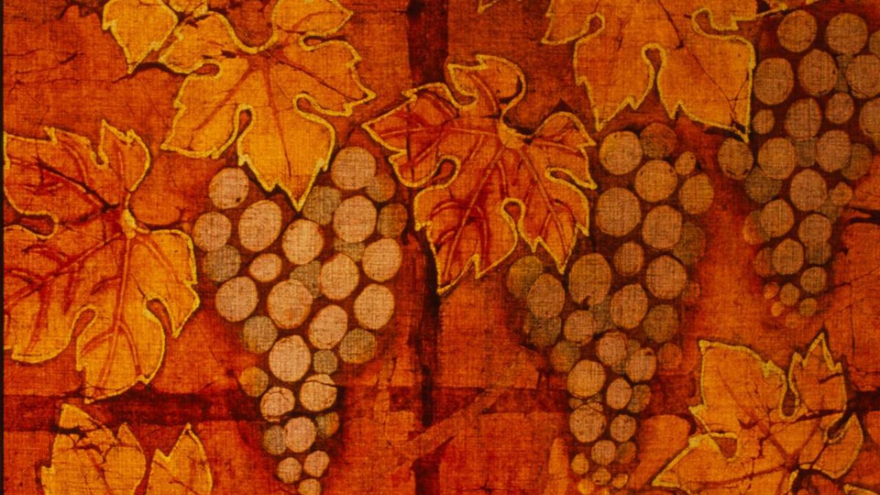 A section of a batik panel depicting maple leaves and bunches of grapes.