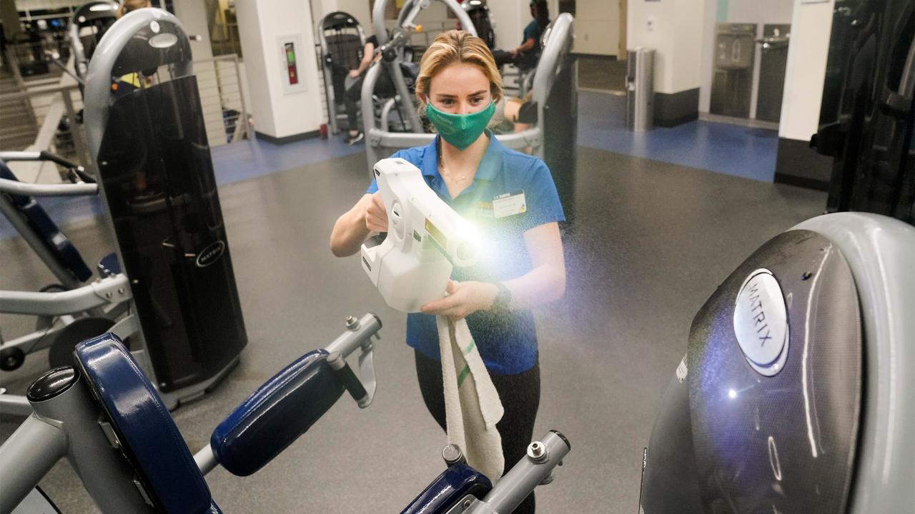 Student disinfects workout equipment at the ARC.