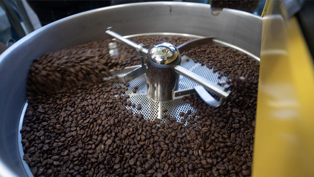 A silver-colored machine turns coffee beans in a circle.
