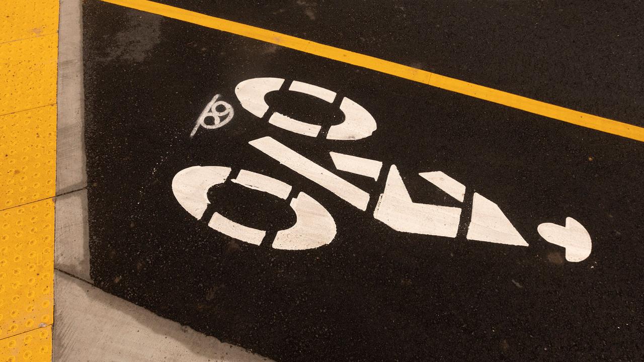 Closeup photo of asphalt with the bike lane symbol painted on it.