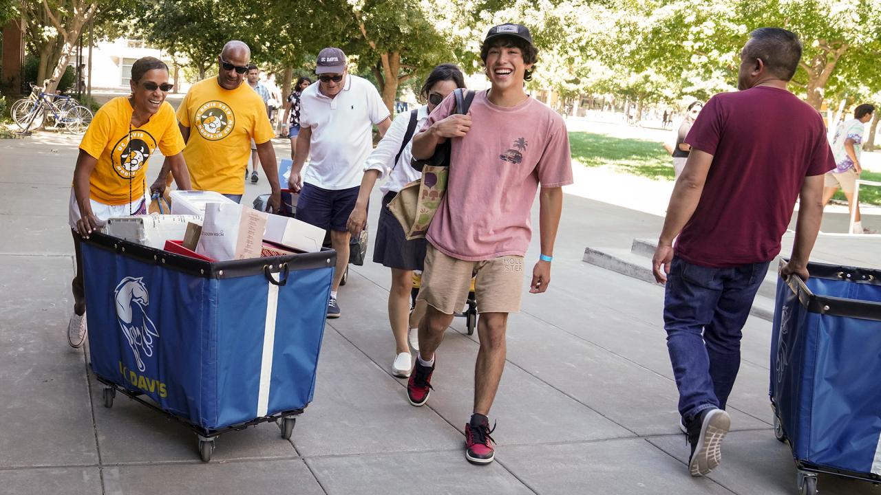 Chancellor Gary S. May and LeShelle May push a cart while helping students move in to campus housing.