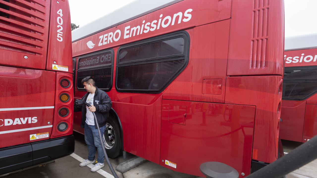 A student recharges an electric Unitrans bus.