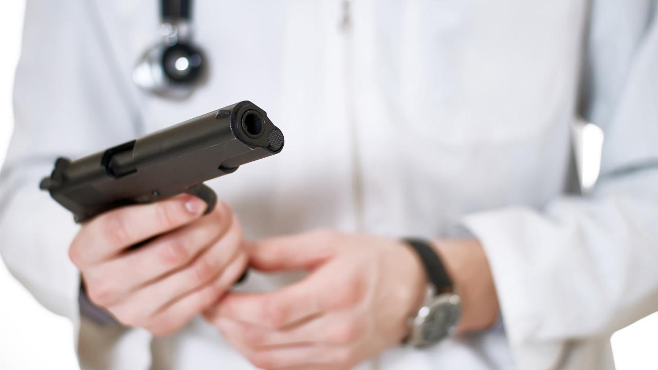 Doctor (white coat, stethoscope) holds gun