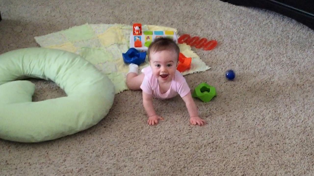 Smiling infant on carpet with toys 