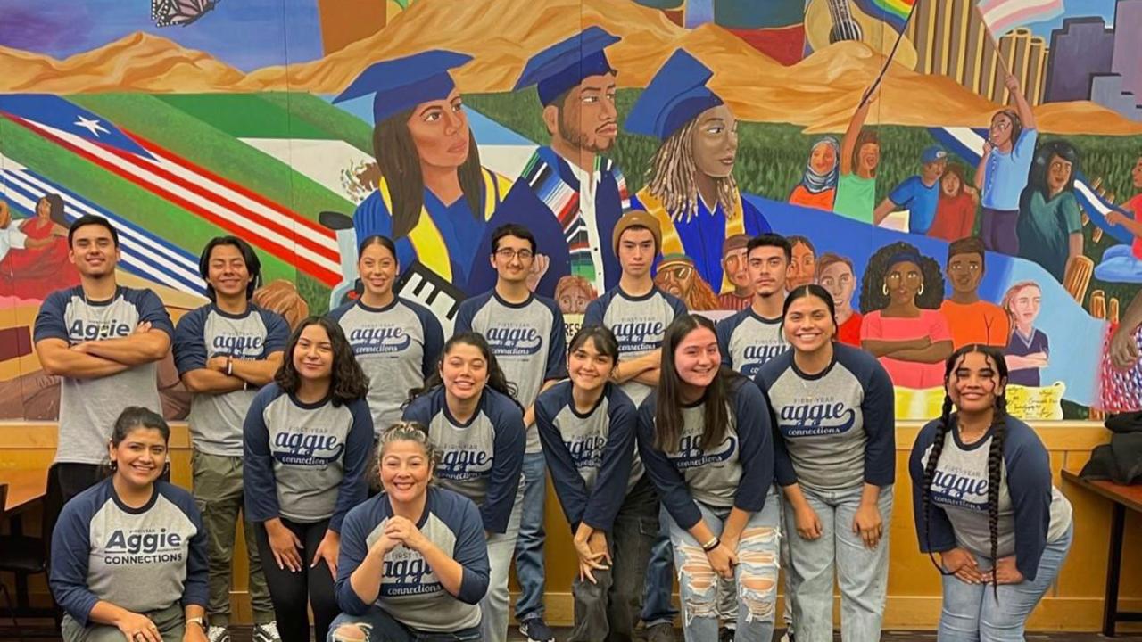 A "connection" poses in front of a campus mural
