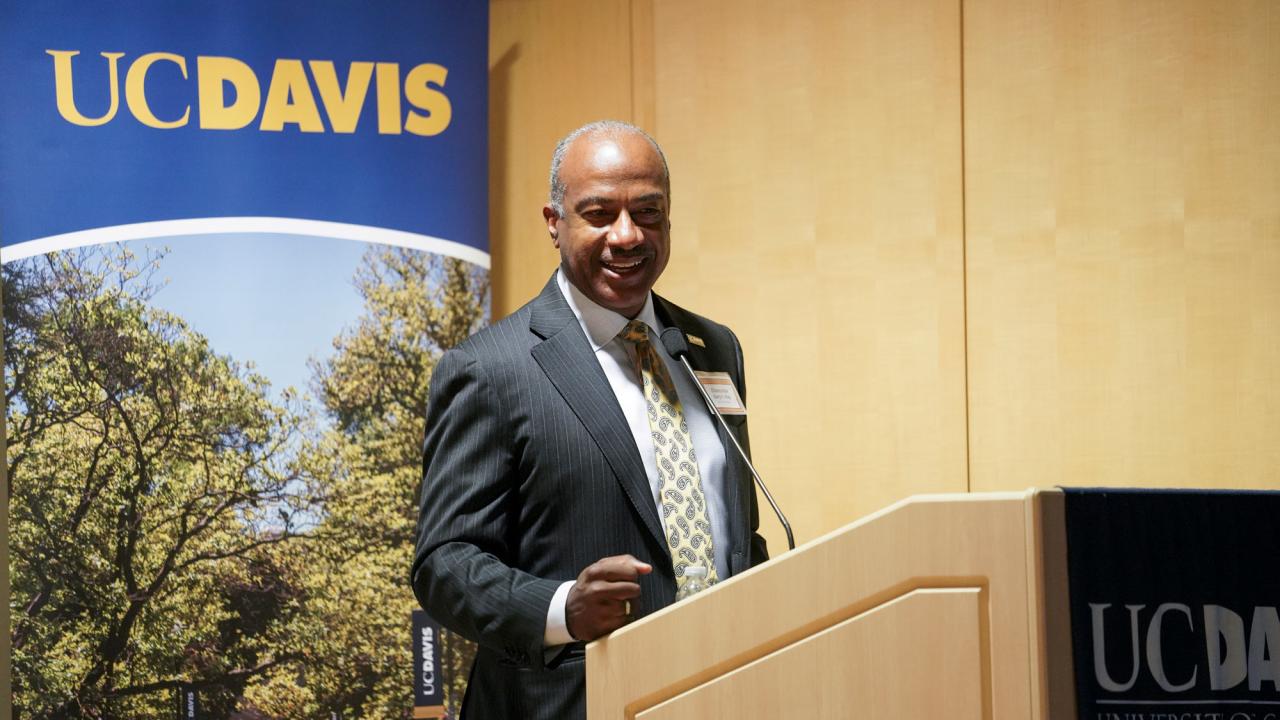 Chancellor Gary S. May at podium, with UC Davis banner behind him