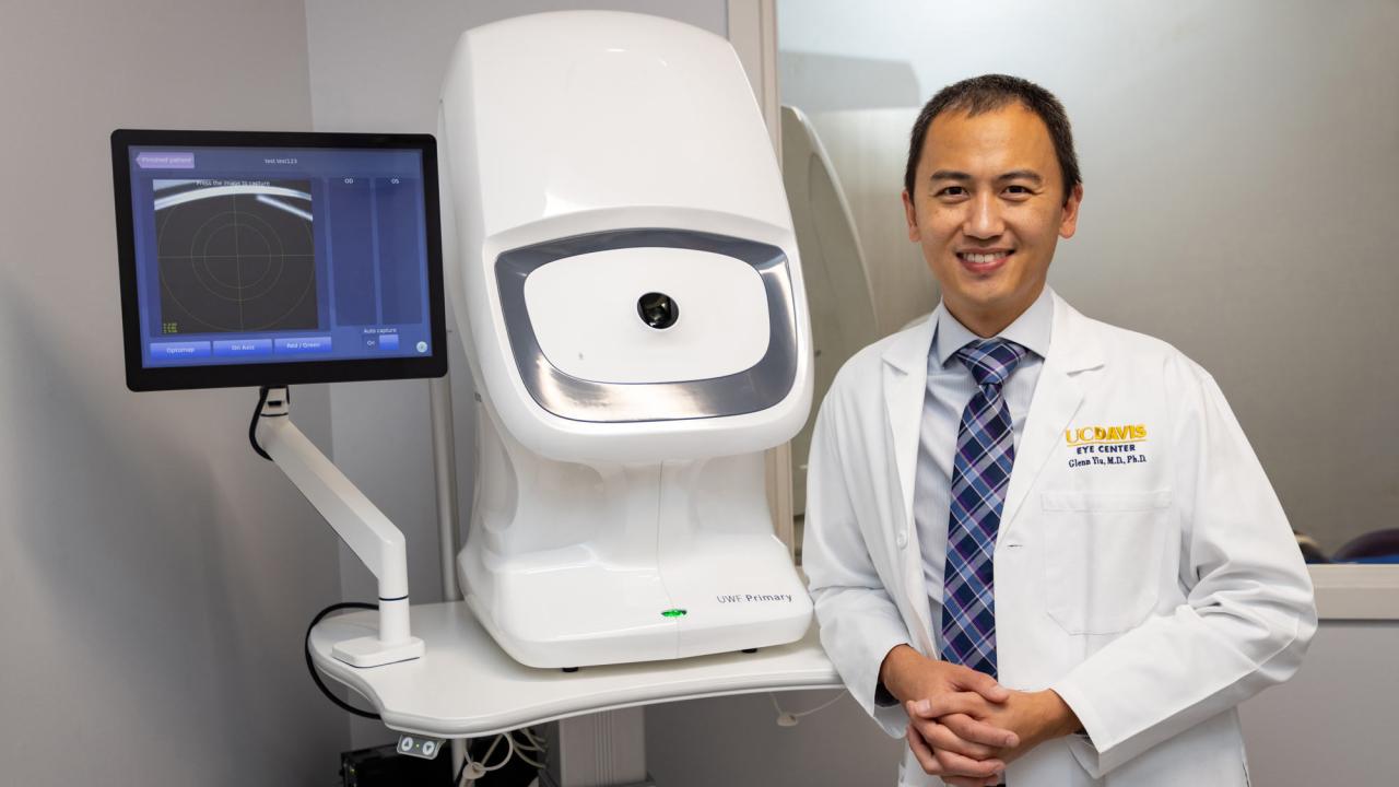 Glenn Yiu, in white lab coat, with ophthalmology equipment, UC Davis Health