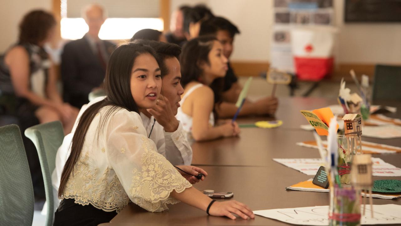 A student in a crowded room reaches for a paper at UC Davis. 