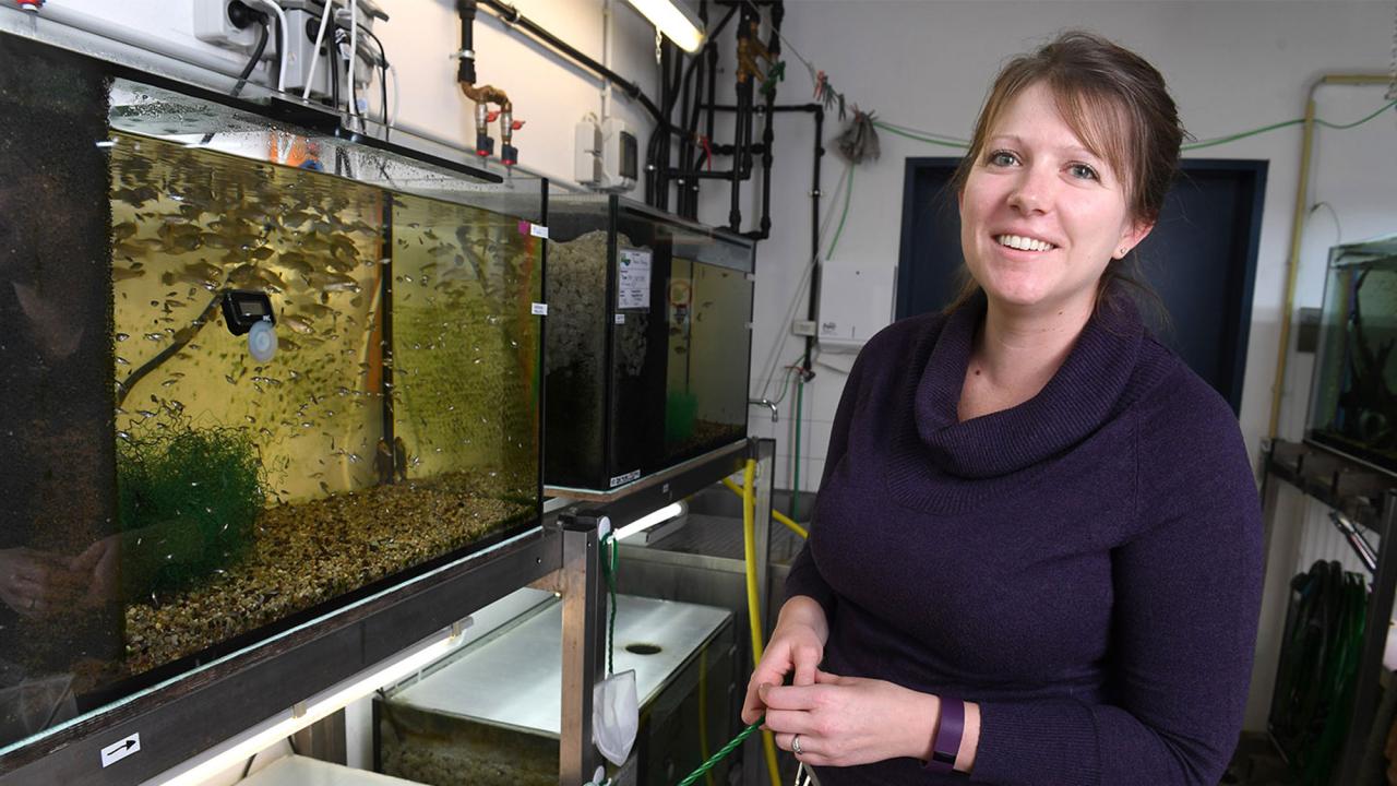 Researcher poses next to fish tan