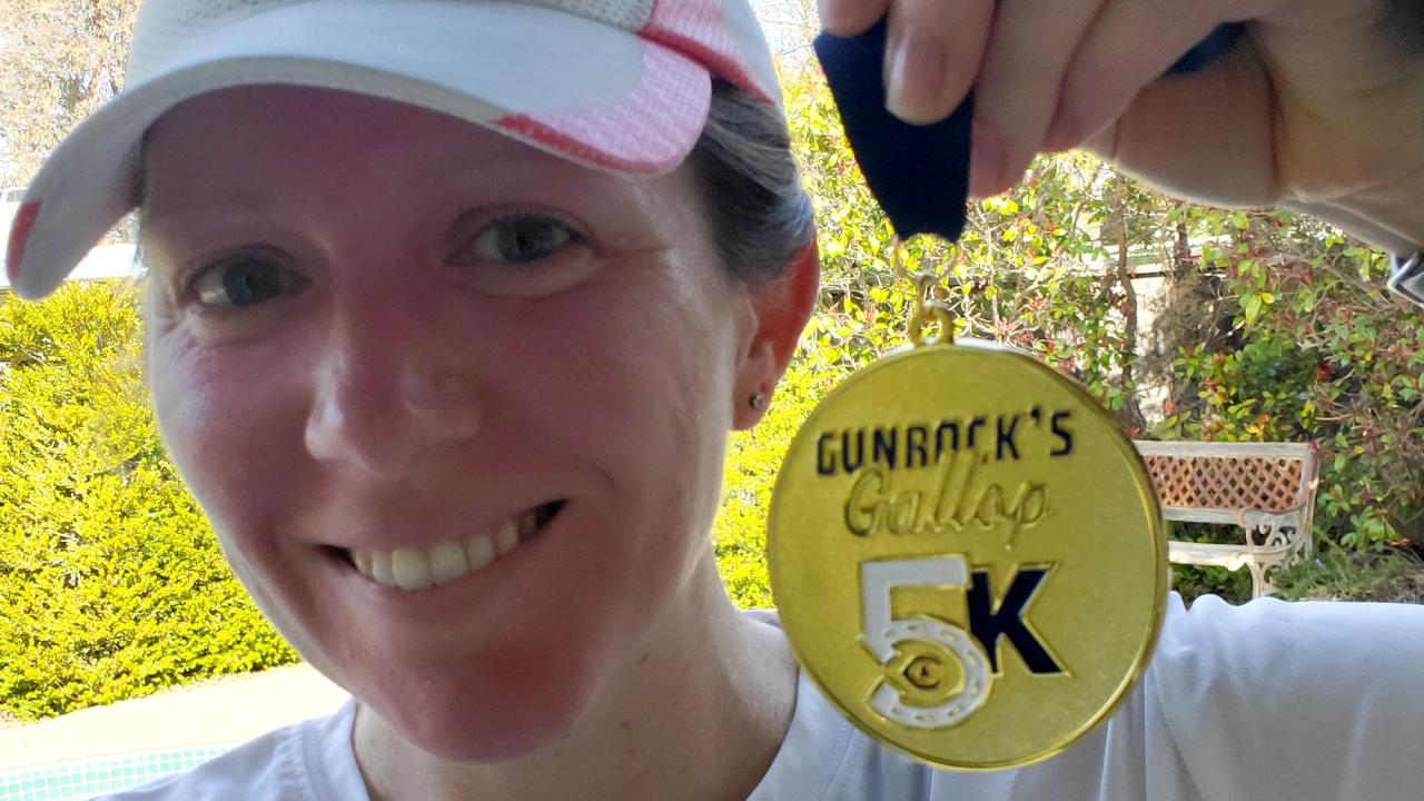 Woman holds Gunrock's Galop 5K medal