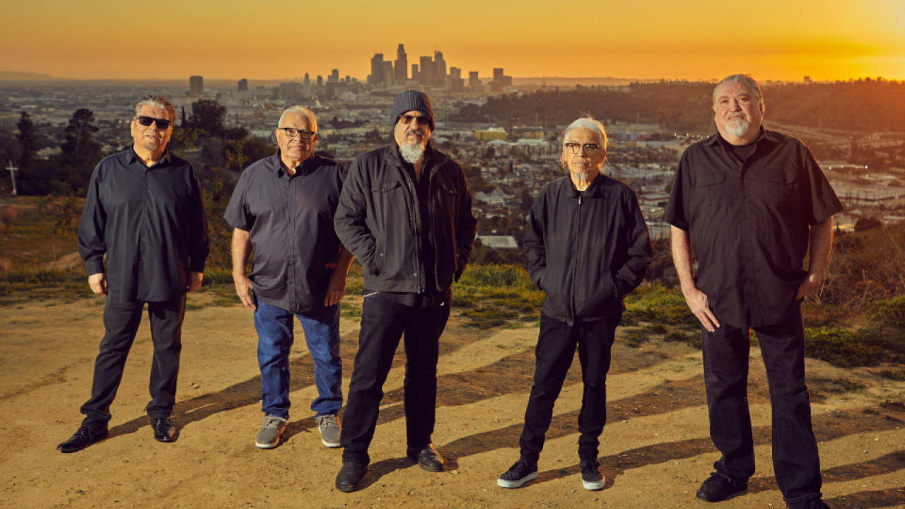Band of men dressed in black with urban scenery behind them