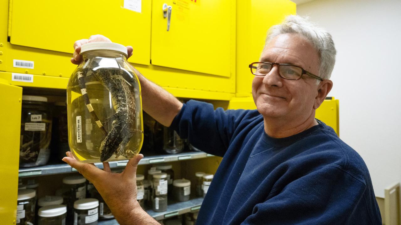 Man holds jar with specimen inside, in liquid