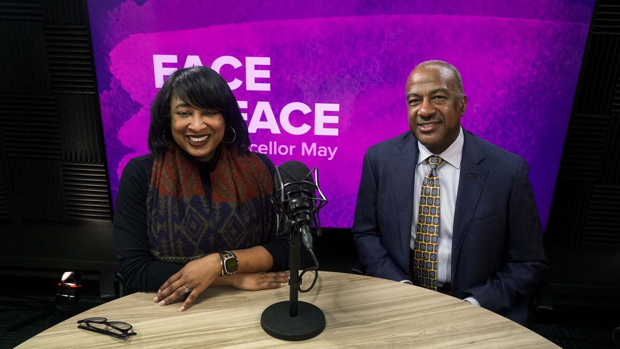Renetta Garrison Tull and Gary S. May sit side-by-side in a video studio, in front of a purple background with the text "Face to Face With Chancellor May"