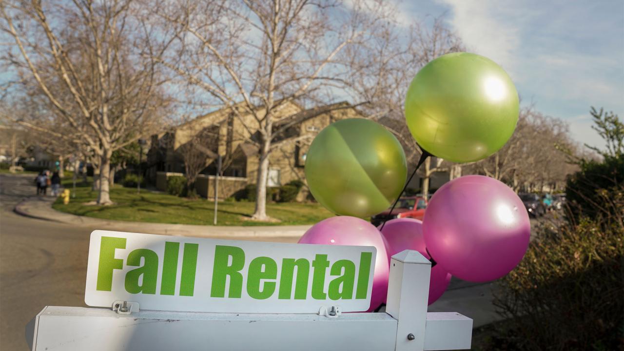 Pink and green balloons draw attention to an apartment rental sign