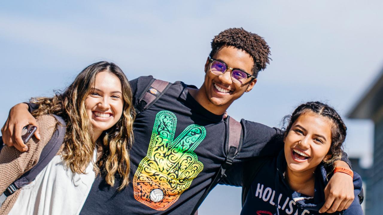 Young man with arms around two women, all three smiling in joyful group shot from report cover
