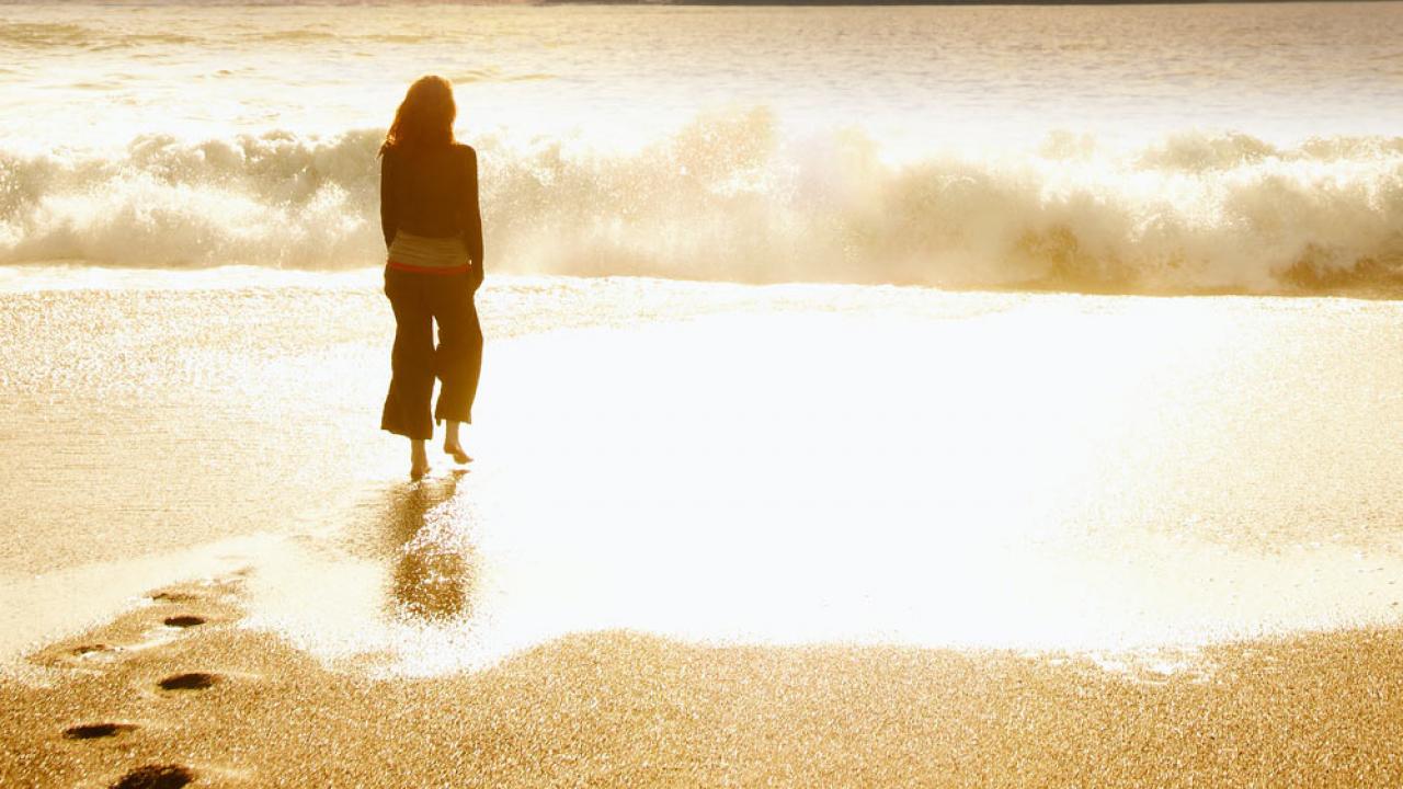 A woman stands on the beach at sunset