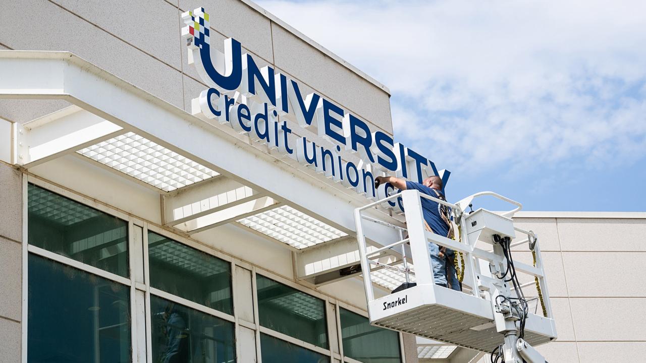 Worker installs University Credit Union Center signage.