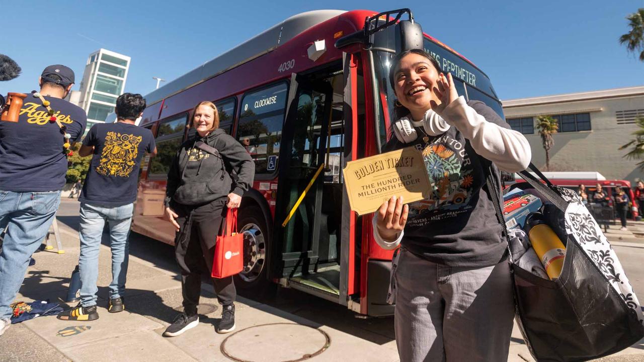 Gabriela Jimenez holds golden ticket near red Unitrans bus.
