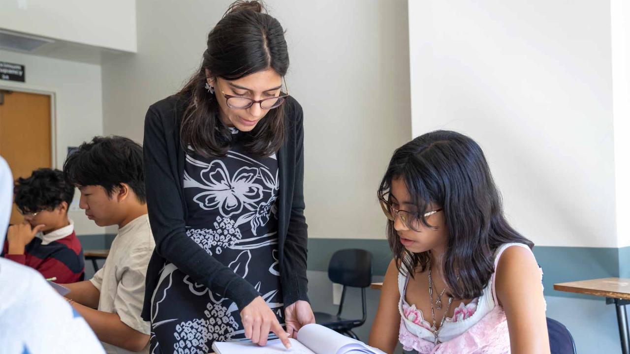 Student helps high schoolers with work in a classroom