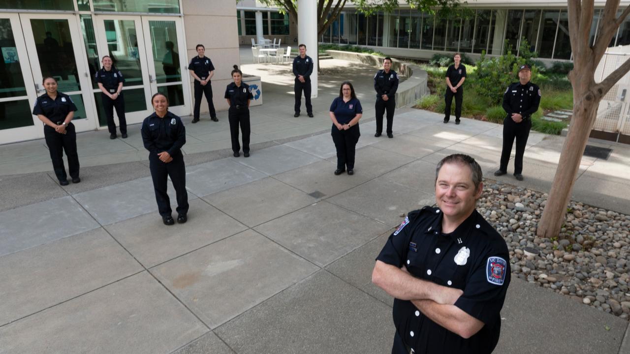 Campus fire personnel, in uniform, posing in semicircle.