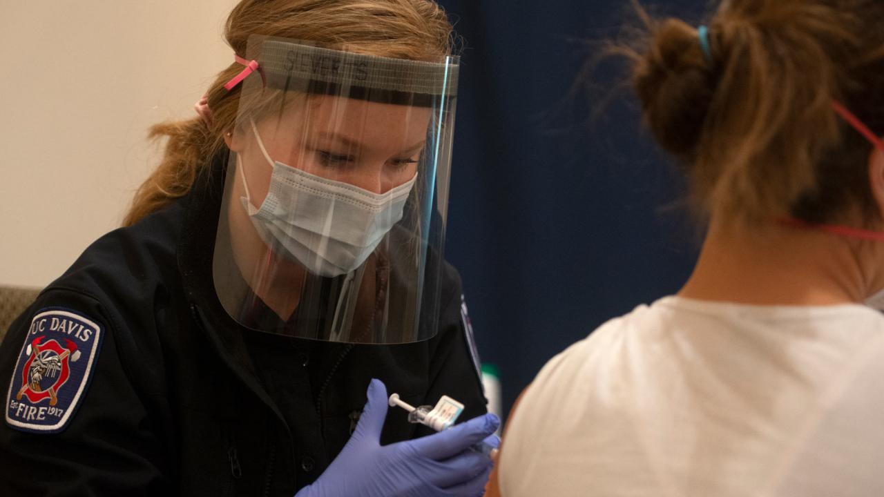 A UC Davis student EMT administering a COVID-19 vaccine at a campus clinic. 