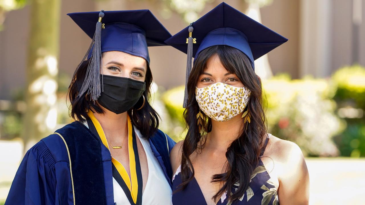 Students wearing face coverings and graduation regalia.