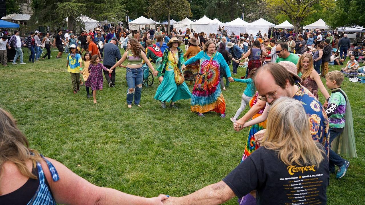 People hold hands and dance on large grassy field