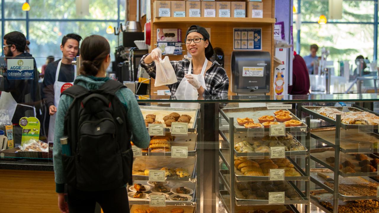 A barista serves a baked good at the Swirlz coffee area of the Coffee House in the Memorial Union at UC Davis.