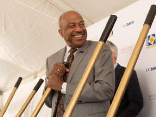 Chancellor Gary S. May, smiling, holding shovel
