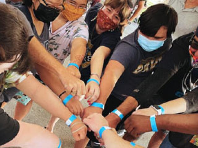 Scholars in all-hands-in circle, showing blue wristbands