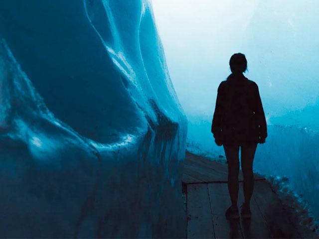 A person stands in awe inside an ice cave