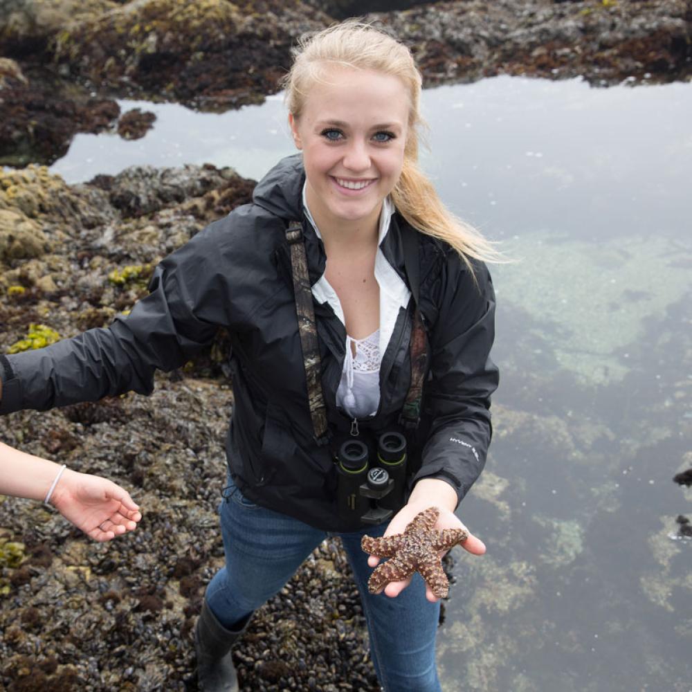 A student holding a sea creature specimen in a Bodega Bay tide pool