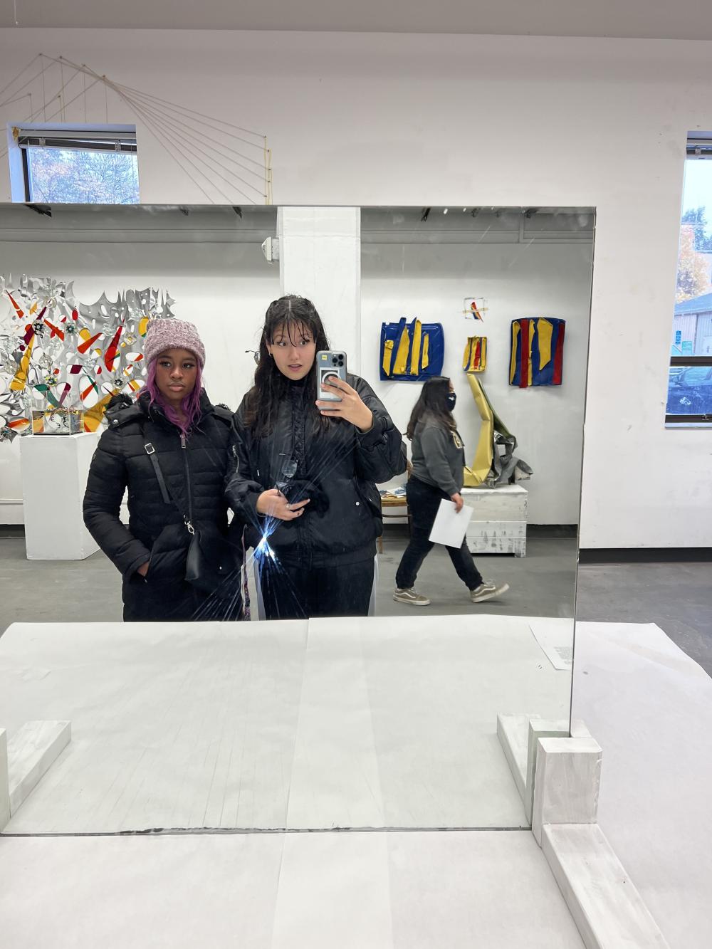 Zoe Vollmer and friend Lee stand in front of a mirror at an art exhibit.