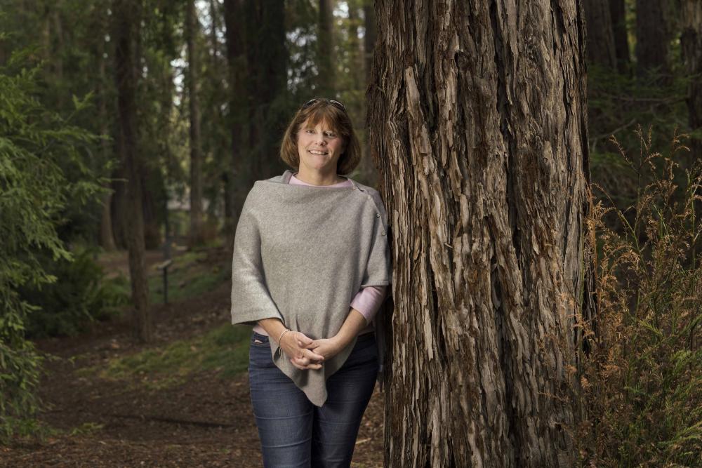 Beth Foraker stands next to a redwood tree