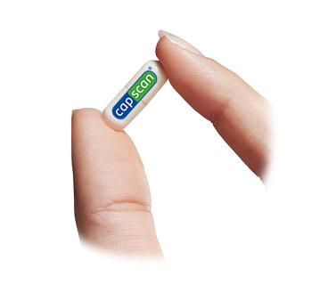 A pill-shape capsule held between thumb and forefinger