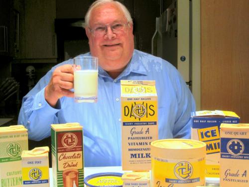 John Bruhn, drinking milk, surrounded by old UC Davis dairy packaging