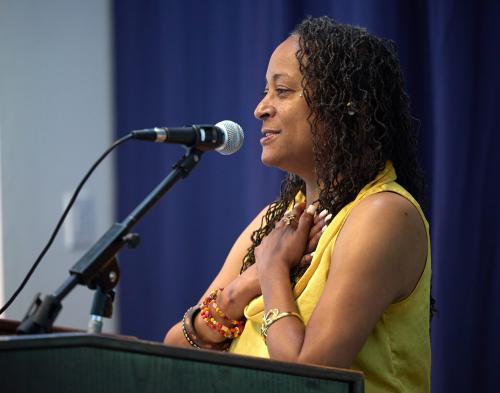 Kristee Haggins holds hands to heart in appreciation, at Soaring to New Heights podium