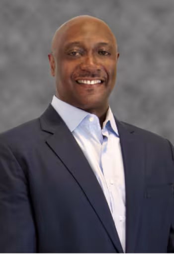 Smiling man in a suit with a gray background.