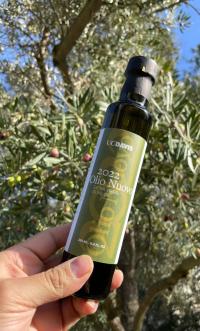"Olio Nuovo" olive oil bottle, slender, green, in hand 