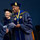 Chancellor Gary May shakes hands as student cross the stage for commencement.