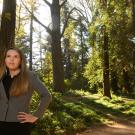 Erica stands with her hands on her hips in the tree-lined arboretum of UC Davis. 