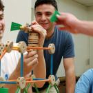 A team of male students using Tinketoys to build a structure