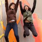 Two women jumping in the air with a colorful mural behind them