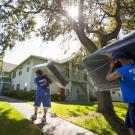 Two movers carry mattresses into apartments