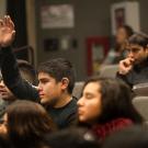 a male high school student raises a hand to ask question