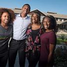 Four African American students standing in front of brown-shingled house