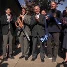 Seven people clap and smile during a ribbon-cutting ceremony.